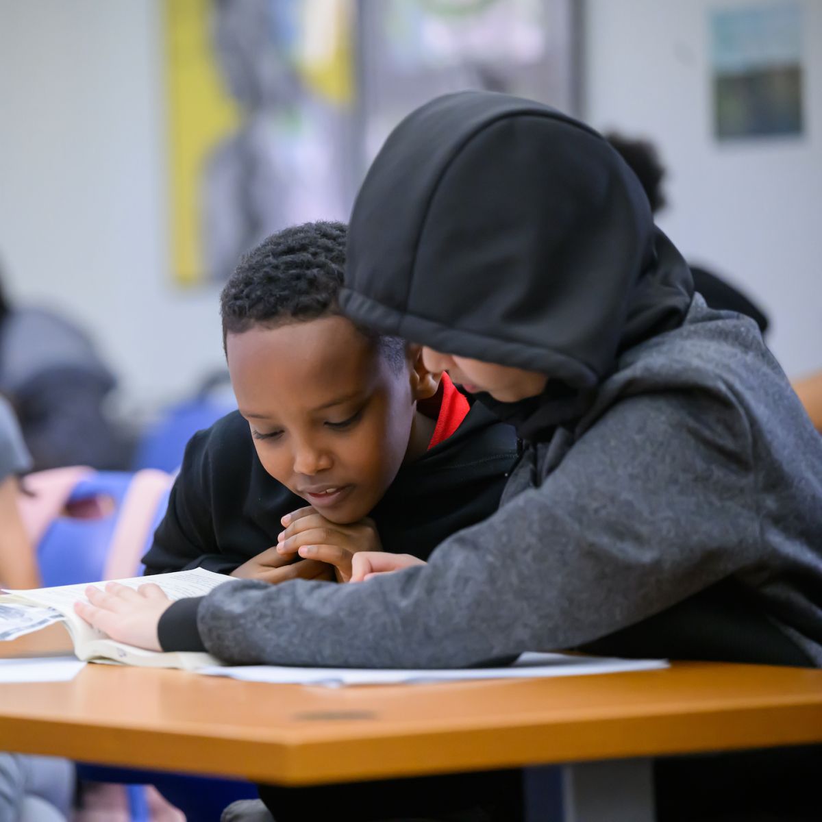 Photo of two students reading a book together