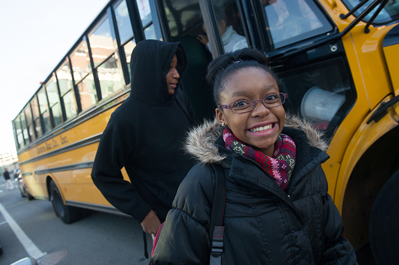 Photo of a smiling girl getting off a school bus