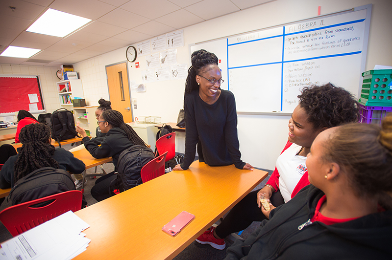 Photo of a teacher smiling while speaking with two smiling students